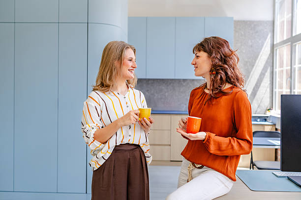 istock Businesswomen engaging in conversation with coffee cups in a modern office setting 2219821129