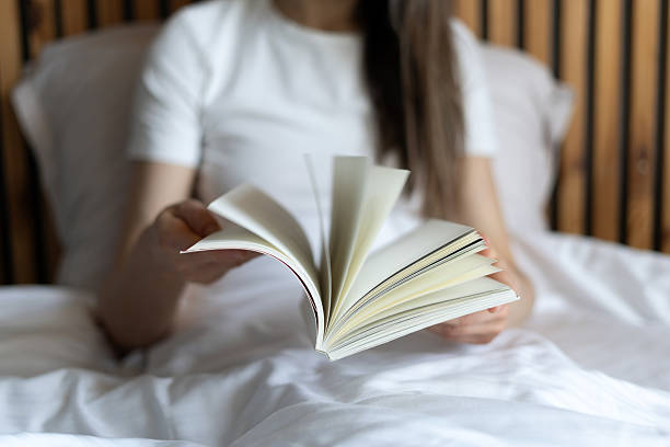 istock Cozy bedroom setting in a hotel room with a guest enjoying a book 2219825414