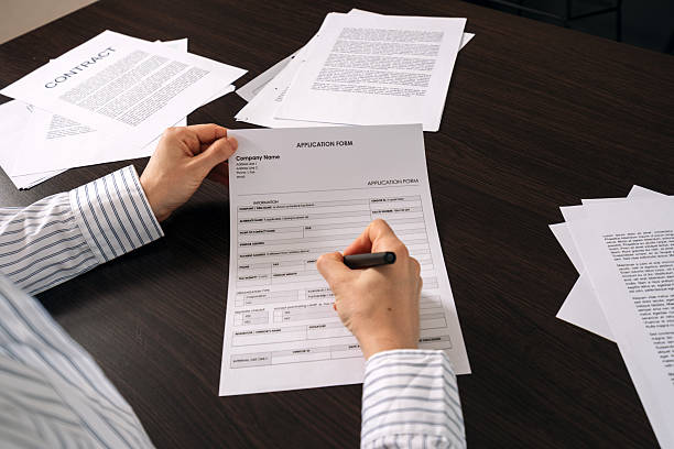 istock Filling out an application form on the office desk with important paperwork nearby 2219825439