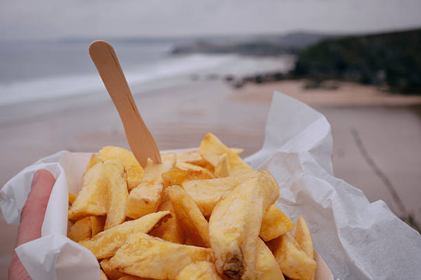 Typical British beach holiday, box of Chips at the beach, Newquay, Cornwall on a rainy overcast day.
