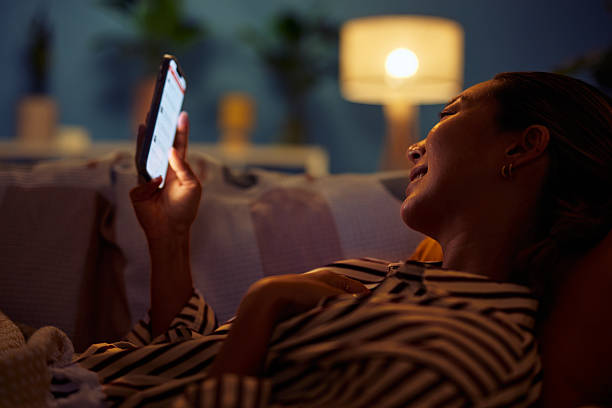 istock Young woman using smartphone late at night in bed smiling 2219827212