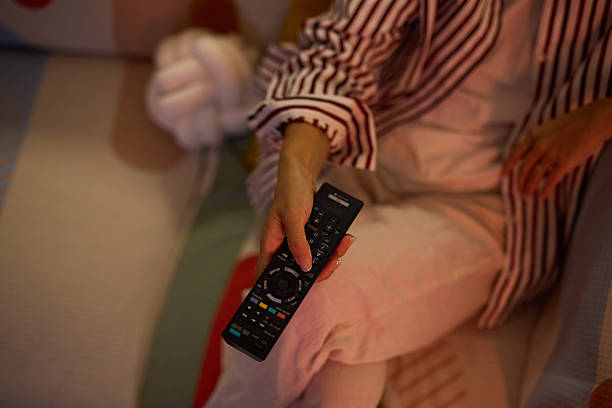 istock Woman holding a remote control while sitting on a sofa 2219828266