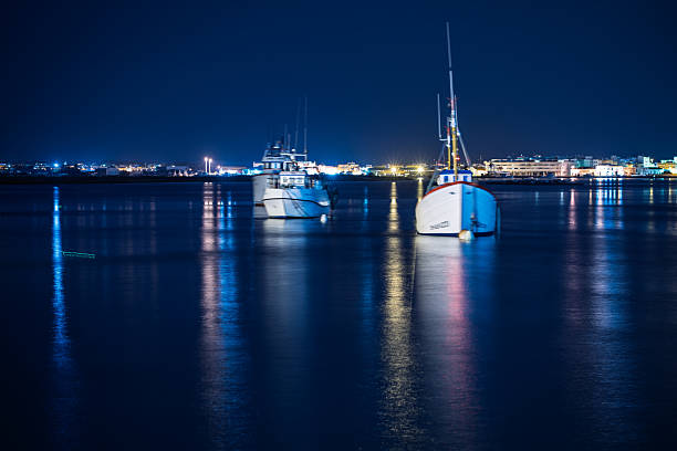 Fishing boats rest peacefully in Punta del Moral, Ayamonte, under a starry sky, their reflections shimmering in the calm waters.