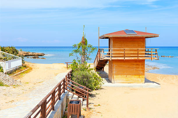 Wooden lifeguard tower on a sandy beach under a clear blue sky in Cyprus, overlooking the calm Mediterranean Sea. Peaceful coastal scene perfect for summer, travel, and vacation themes