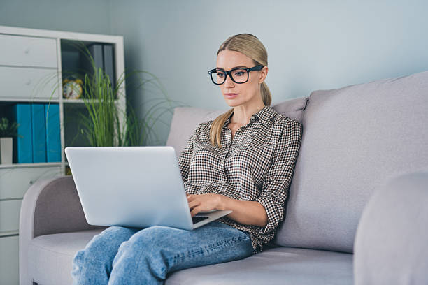 istock Photo of focused smart marketer lady agent sit couch use netbook watch education tutorial in house indoors 2219829409