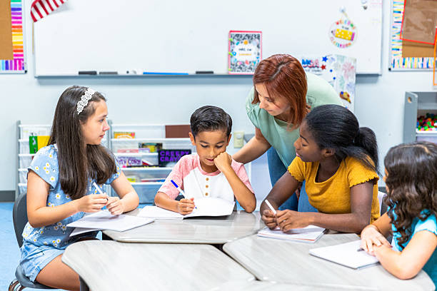 istock Young female teacher working with her students on a writing lesson in school 2219832928