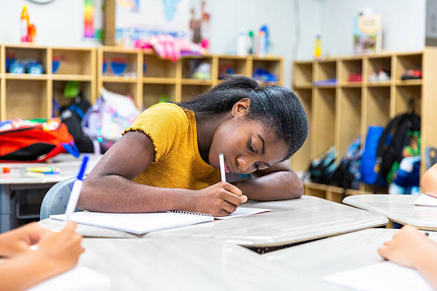 Young black girl writing in her notebook at school