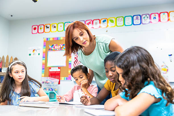 istock Young female teacher working with her students on a writing lesson in school 2219833248