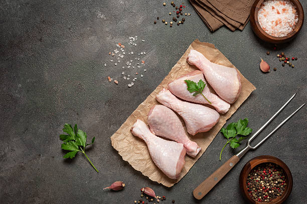 istock Raw chicken drumsticks on dark rustic background with spices flat lay 2219837331