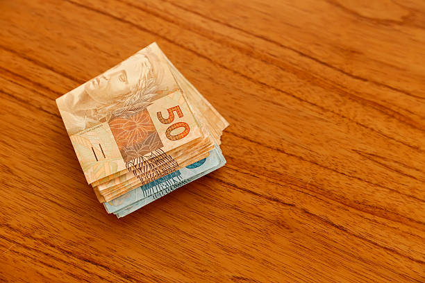 Folded one hundred and fifty real bills spread on wooden table, highlighting the fifty real notes, perfect for finance and economy themes in Brazil