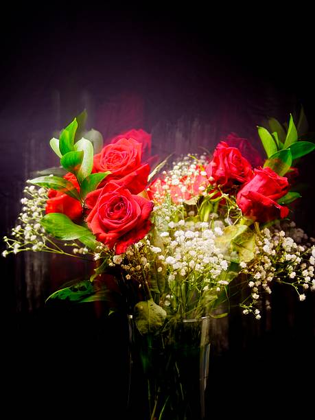 An abstract motion blur photo of a bouquet of roses against a dark background.