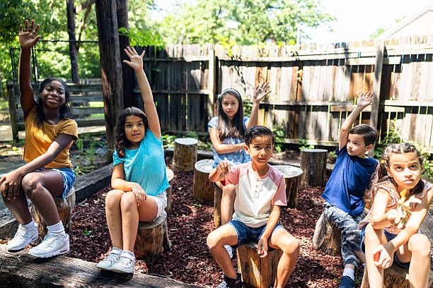 Young elementary students listening to their teacher at an outdoor nature classroom setting
