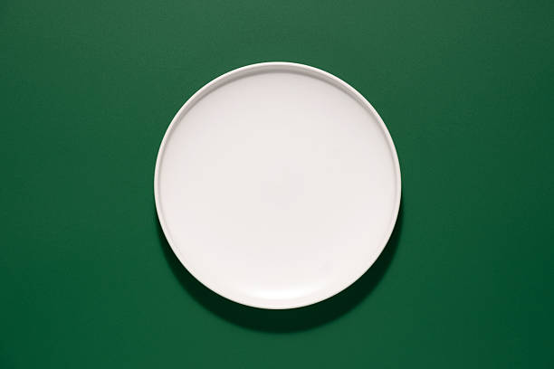 istock Empty round white plate on green background ready for serving food or appetizers during a meal 2219850308