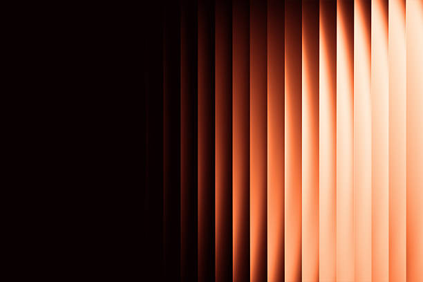 Vertical bands of warm tones ranging from orange to a lighter shade on the right, set against a dark background. The bands appear translucent with ripple-like patterns, suggesting light refraction, conveying an elegant and warm design.