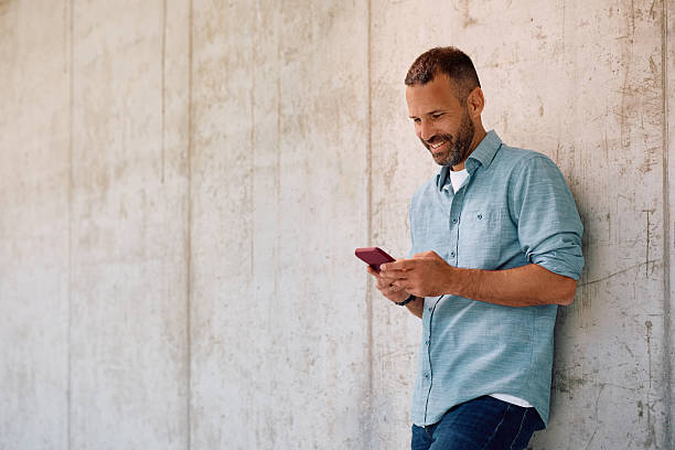 istock Happy entrepreneur texting on cell phone against the wall. 2219850969