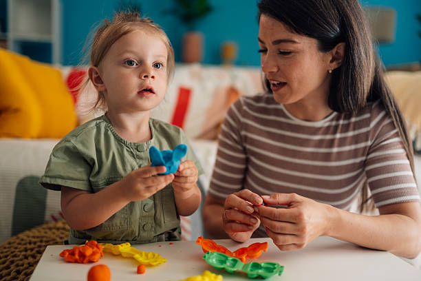istock Mother and daughter playing with modeling clay at home 2219858277