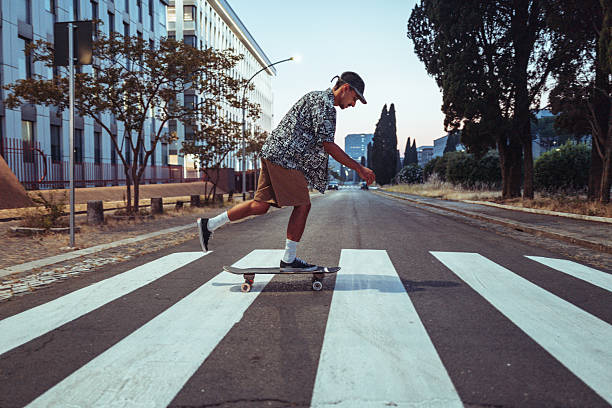 istock Young Man Skateboarding Through City Crosswalk at Sunset 2219858480