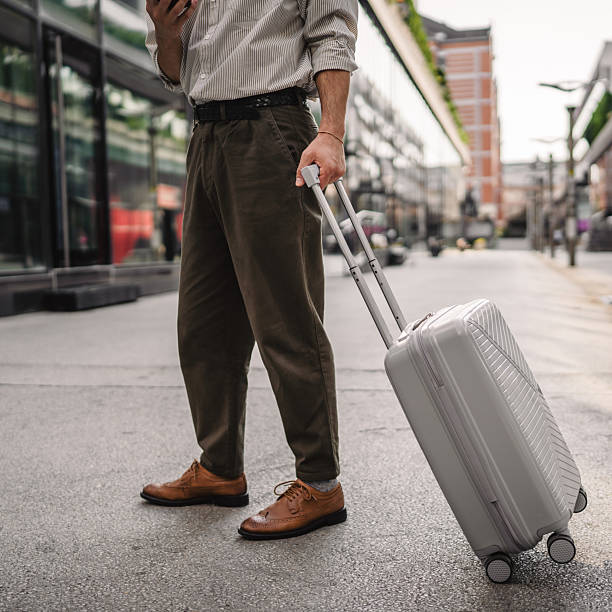 istock unknown man walk down the street with a suitcase and use cellphone 2219860402