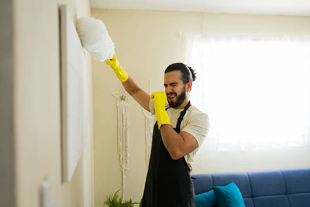istock Latin man cleaning wall with duster having allergy symptoms at home 2219861063