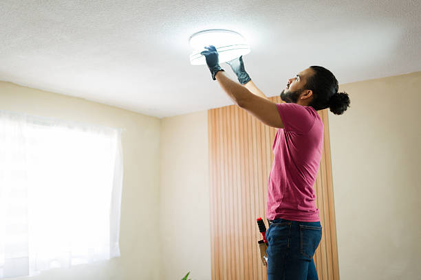 istock Electrician installing ceiling light fixture in modern home 2219863475