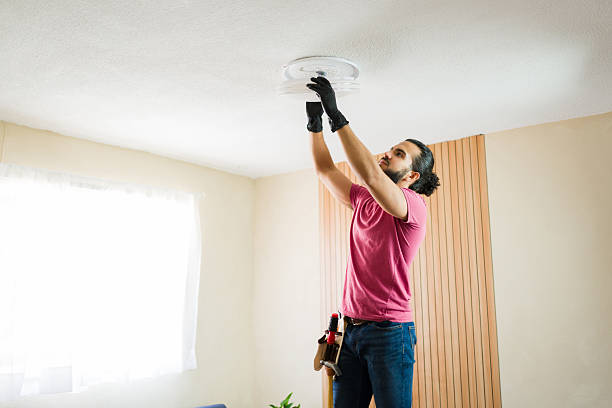istock Latin man installing ceiling light fixture in residential home 2219863483