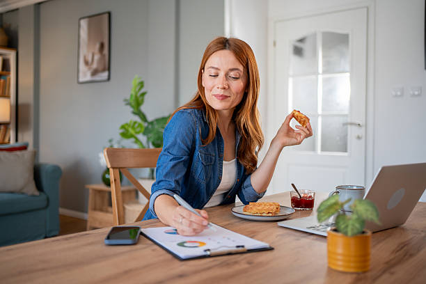 istock Businesswoman working from home and having breakfast while analyzing charts 2219864275