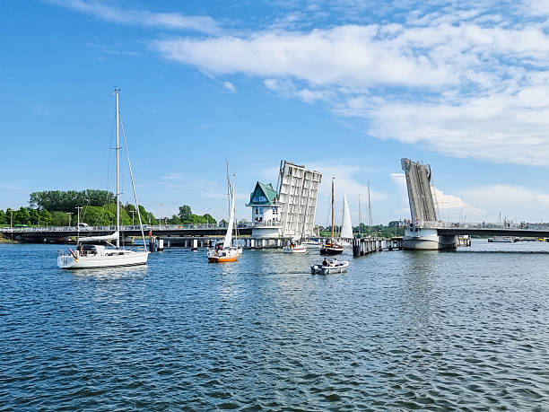 Sailboats and motorboats queueing on the Schlei river waiting for the bascule bridge to open in Kappeln, Germany.