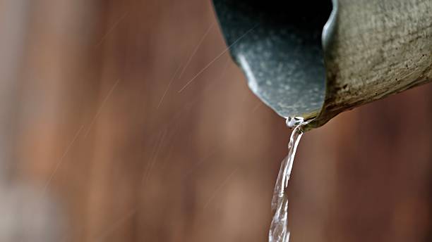 istock Close-Up Of Rain Water Flowing From Metal Gutter Pipe 2219866034