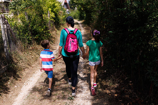 Mother and two children walking under the trees of cherry blossom