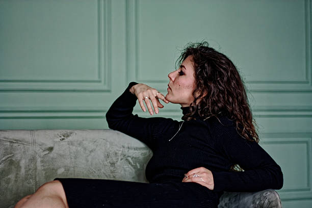 istock Young woman sitting on the green sofa 2219871840