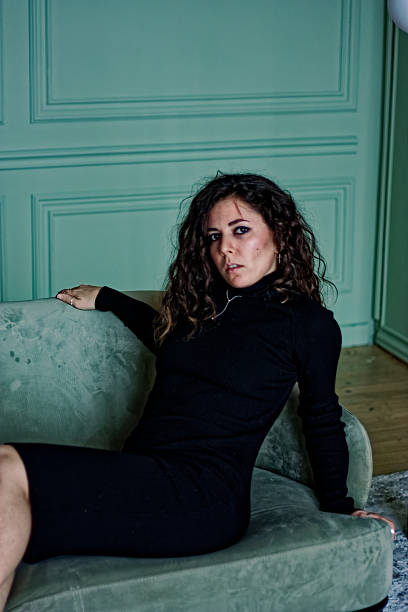 istock Young woman sitting on the green sofa 2219871841