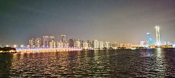istock Modern riverside building illuminated at night, surrounded by trees and reflections on calm water, with peaceful ambiance and soft lighting 2219874062