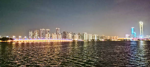 istock Modern riverside building illuminated at night, surrounded by trees and reflections on calm water, with peaceful ambiance and soft lighting 2219874071