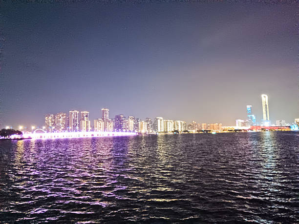 istock Modern riverside building illuminated at night, surrounded by trees and reflections on calm water, with peaceful ambiance and soft lighting 2219874073