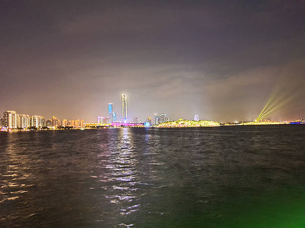 Modern riverside building illuminated at night, surrounded by trees and reflections on calm water, with peaceful ambiance and soft lighting