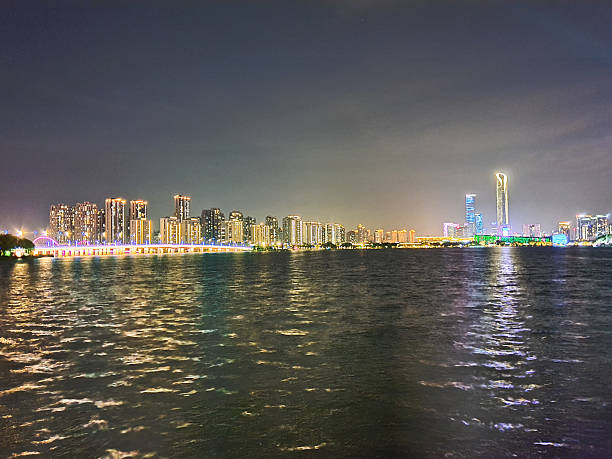 istock Modern riverside building illuminated at night, surrounded by trees and reflections on calm water, with peaceful ambiance and soft lighting 2219874089