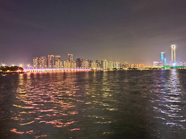 istock Modern riverside building illuminated at night, surrounded by trees and reflections on calm water, with peaceful ambiance and soft lighting 2219874130