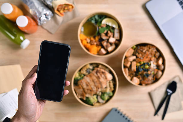istock People eating healthy meal while working, hand holding phone for copy space 2219882274
