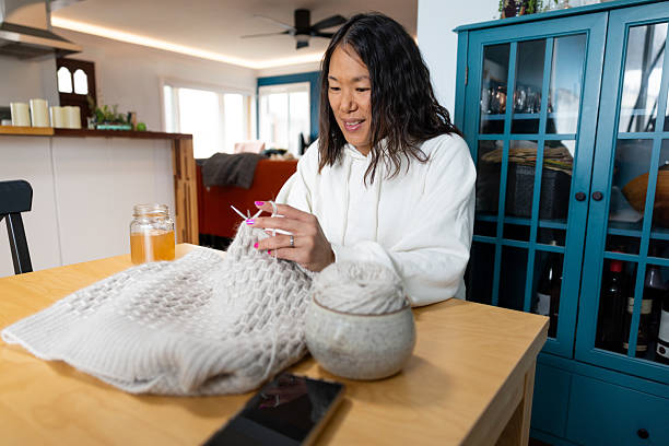 Candid photo of a Asian woman knitting  in her relaxing and comfortable home.