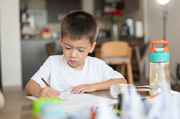 istock Focused Child Coloring at Table Surrounded by Art Supplies 2219887536