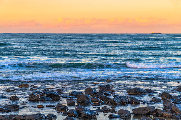 Sunset at Towradgi Beach with black rocks in the City of Woolongong, NSW, Australia. Towradgi is derived from the Dharawal word Kow-radgi, meaning guardian of the sacred stones.
