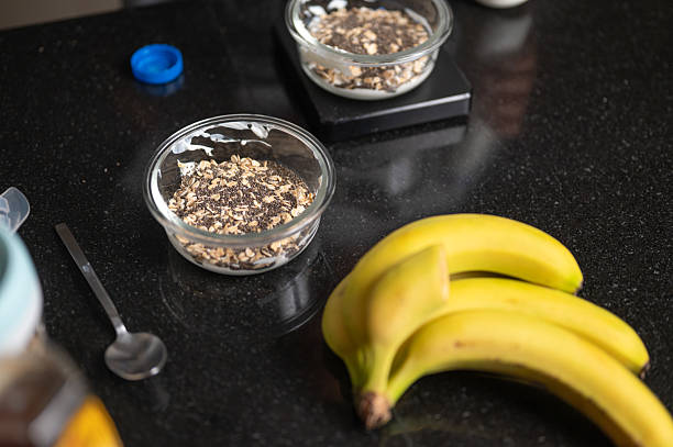 rClose-up of a bowl with oats, Greek yogurt, and chia seeds, with a banana nearby, during the preparation of a nutritious overnight oats breakfast.