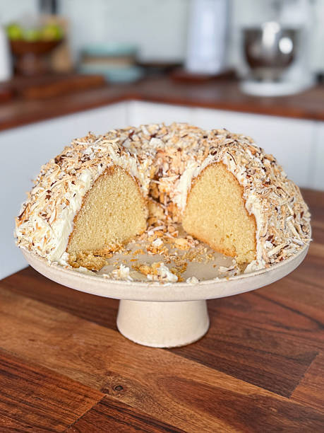 Image of homemade coconut sponge cake in bundt ring tin with butter icing, cream, roasted coconut flakes