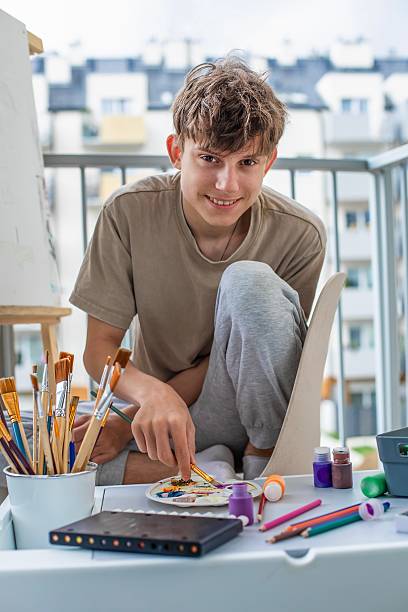istock Teenager with easel mixing colored paints for drawing 2219895752