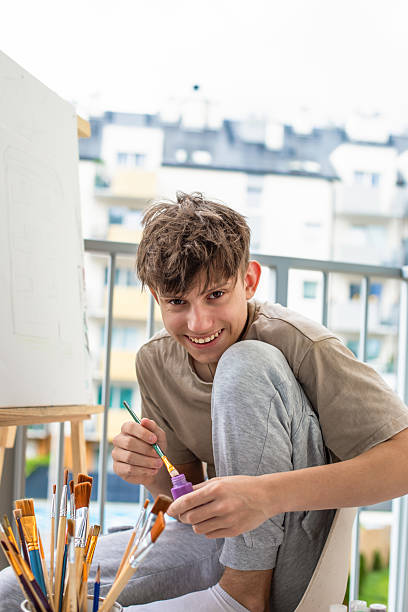 Teenager with easel mixing colored paints for drawing