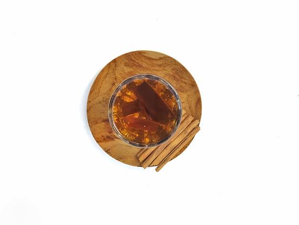A pile of orange slices and cinnamon sticks on a white background. The oranges are cut in half and the cinnamon sticks are whole. Concept of warmth and comfort