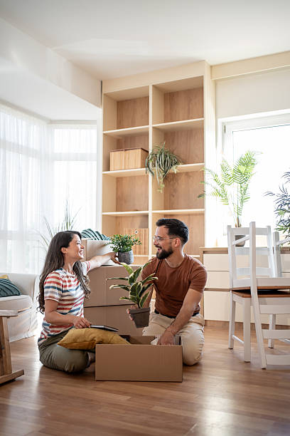 istock Young couple unpacking boxes and arranging plants in new apartment 2219907556