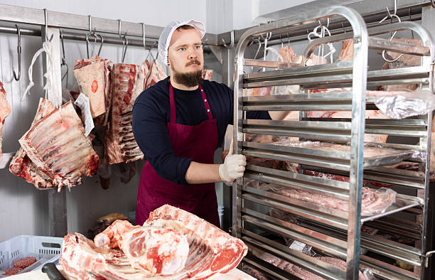 istock Butcher shop worker organizing meat racks in cold storage 2219908774