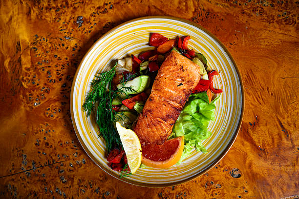 Baked salmon garnished with lemon, pepper and tomatoes with herbs