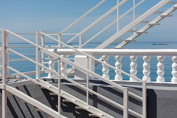 Staircase with vibrant yellow markings leads towards sandy Malibu beach, where gentle ocean waves create a calming retreat for beachgoers.